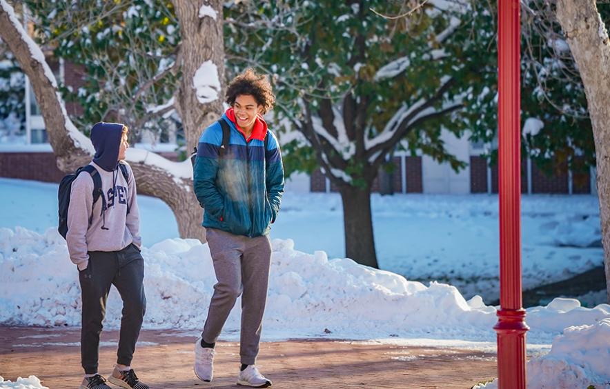 two students walking on campus with snow in background